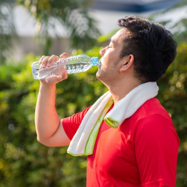 Parkta açık bir şişe su içme Asain spor adamı.