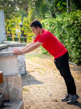 Mutlu Asya spor adam doning egzersiz açık parkta.