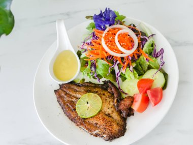 Izgara balık biftek salata mermer masa üzerinde beyaz plaka ile.