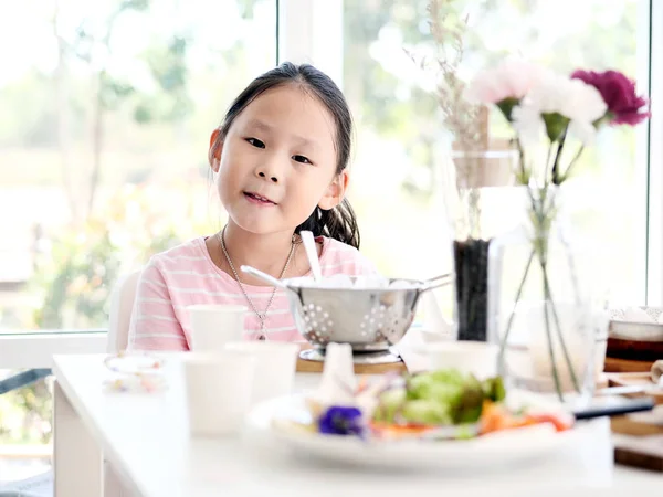 自宅の窓の近くの食べ物を食べるアジアの女の子 — ストック写真