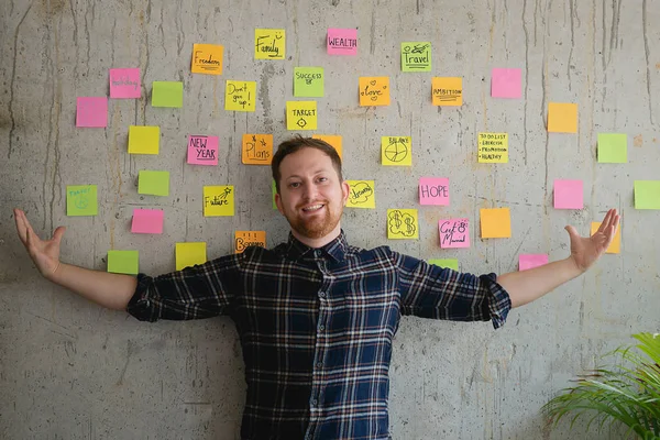 Happy man present his sticky notes chart on cement wall.  Entrepreneur concept