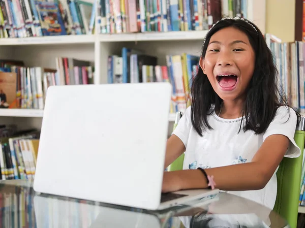 Glad Flicka Usning Laptop Bord Med Bokhyllan Bakgrund Utbildning Koncept — Stockfoto