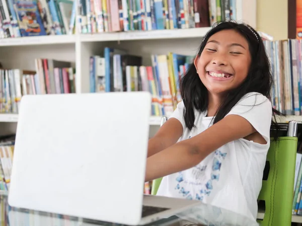 Glad Flicka Usning Laptop Bord Med Bokhyllan Bakgrund Utbildning Koncept — Stockfoto