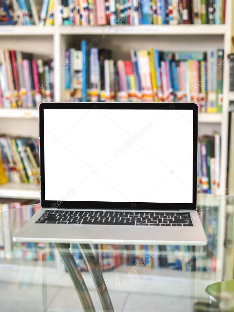 Blank laptop on glass table with bookshelf background.