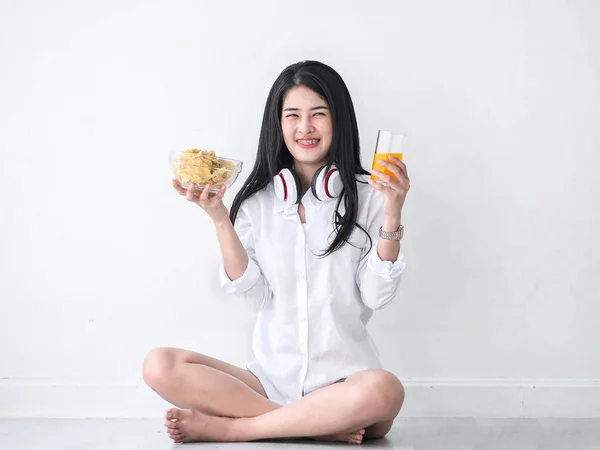 Felice donna asiatica in possesso di un bicchiere di succo d'arancia e chi di patate — Foto Stock
