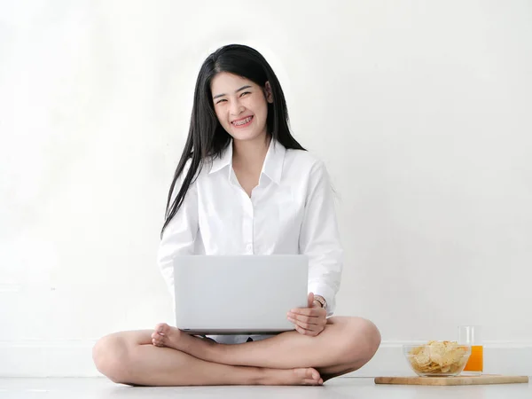 Mujer asiática feliz en camisa blanca usando el ordenador portátil en el suelo en casa . — Foto de Stock