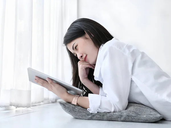 Mooie Aziatische vrouw liggend op de vloer en het gebruik van Tablet PC thuis. — Stockfoto