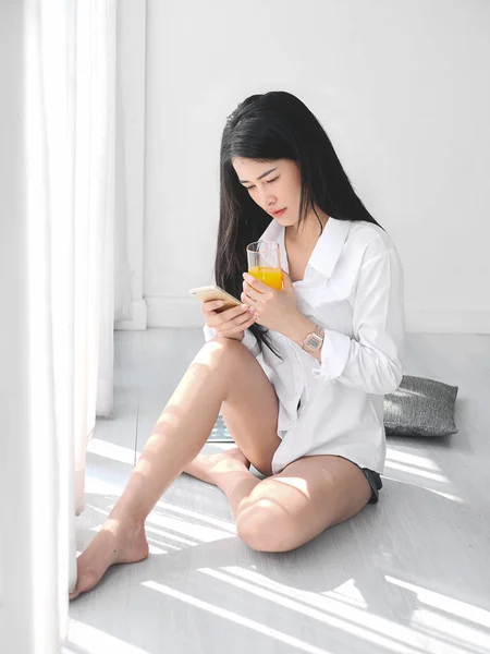 Glad asiatisk kvinna med smartphone och hålla ett glas apelsin — Stockfoto