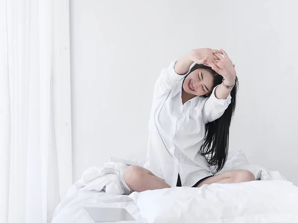 Gadis Asia yang menarik duduk di tempat tidur putih dan bersantai di rumah . — Stok Foto