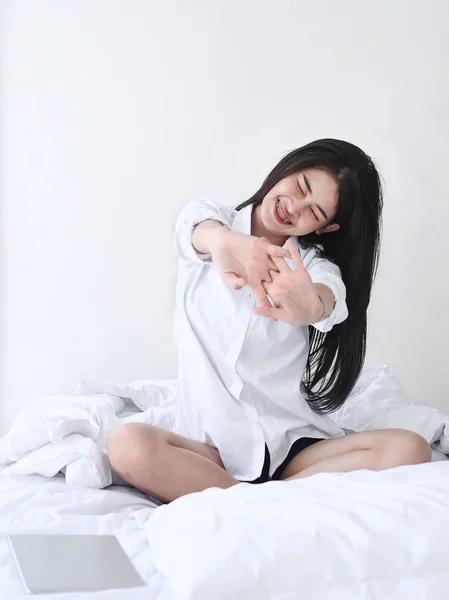 Menina asiática atraente sentado na cama branca e relaxar em casa . — Fotografia de Stock