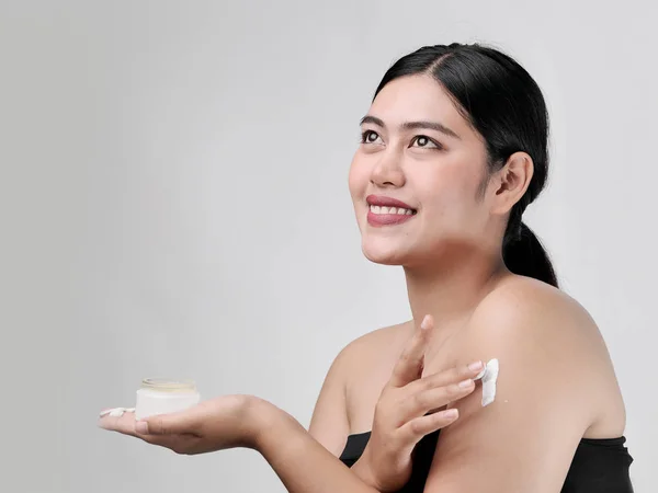 Beauty portrait of Asian smile beautiful woman applying moisturi