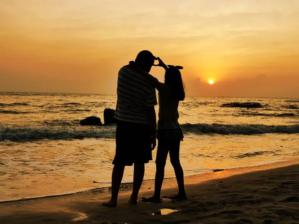 Silhueta menino e menina com as mãos sinal de amor na praia ao sol — Fotografia de Stock