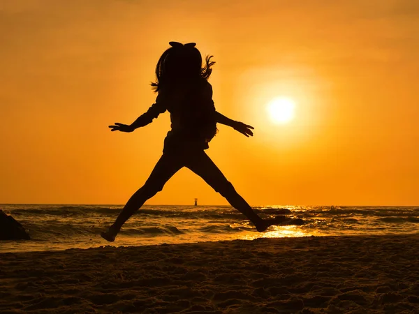 Silhueta menina dança e pulando na praia ao nascer do sol . — Fotografia de Stock