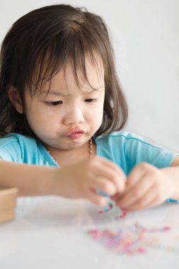 Asyalı kız yaşam tarzı konsepti cam boncuk evde oynarken.