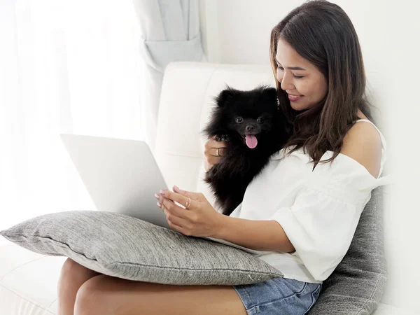 Mulher asiática feliz usando laptop com seu cão no sofá em casa, lif — Fotografia de Stock