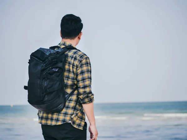 Baksidan av asiatiska man med ryggsäck står och tittar på strand — Stockfoto