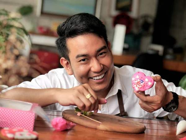Feliz hombre asiático decorando galletas de San Valentín en casa, estilo de vida —  Fotos de Stock
