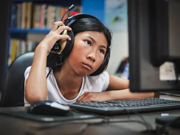 Asiatique fille en utilisant casque avec ordinateur portable à la maison . — Photo
