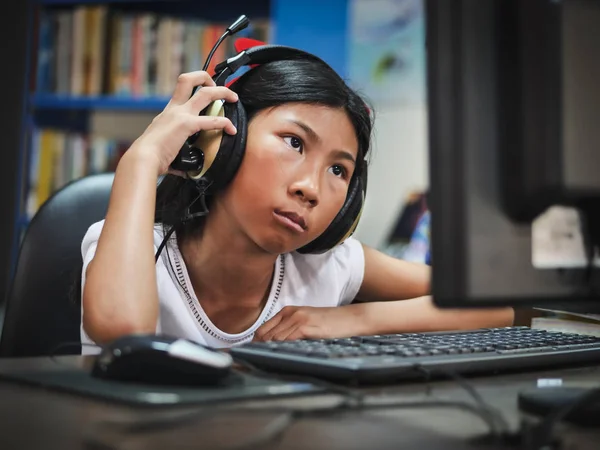 Aziatisch meisje hoofdtelefoon met laptop thuis. — Stockfoto