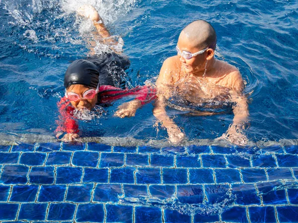 Niños felices aprendiendo a nadar en la piscina en un día soleado . —  Fotos de Stock