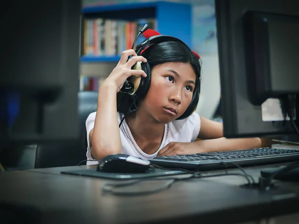 Aziatisch meisje hoofdtelefoon met laptop thuis. — Stockfoto