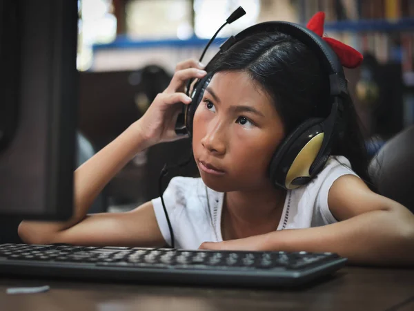 Aziatisch meisje hoofdtelefoon met laptop thuis. — Stockfoto