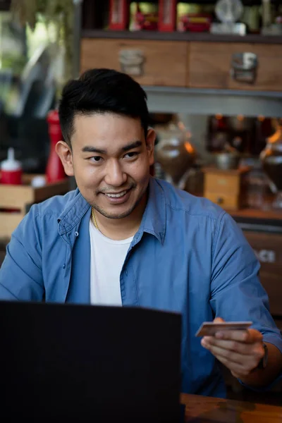 Making online bank transfer, man holds a credit card while enter