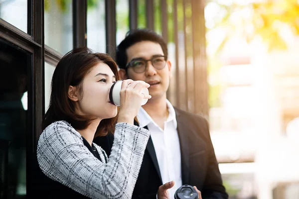 Mujer de negocios sosteniendo la taza de café y hablando con su equipo outd —  Fotos de Stock