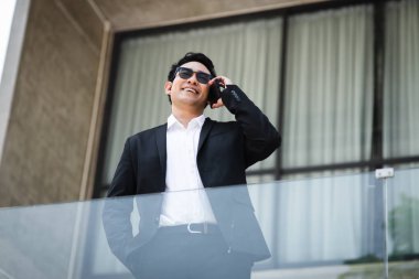 Backgro bina ile telefon ile konuşurken akıllı Asya iş adamı