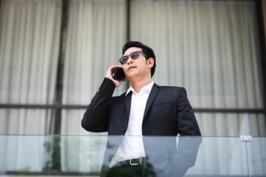 Backgro bina ile telefon ile konuşurken akıllı Asya iş adamı