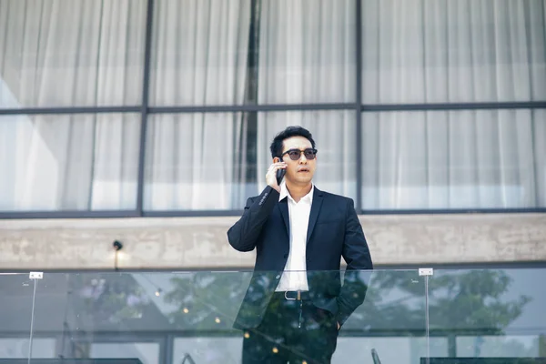 Chytré asijský podnikatel mluvil telefonem s budování backgro — Stock fotografie
