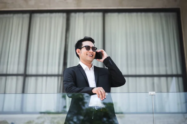 Inteligente asiático hombre de negocios hablando con el teléfono con backgro edificio — Foto de Stock