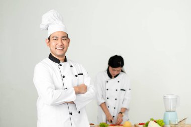 Kendine güvenen Asya Şef ile onun yardımcısı adam kameraya bakıyor