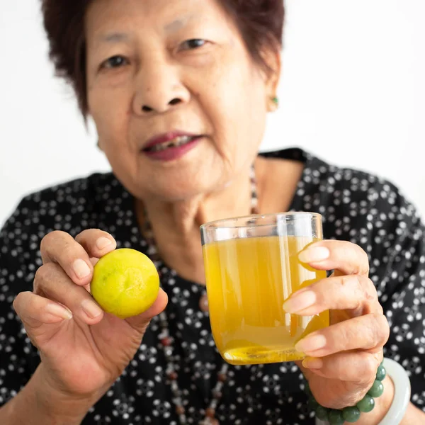 Asiática senior mujer holding limón y miel jugo en vidrio en hom —  Fotos de Stock