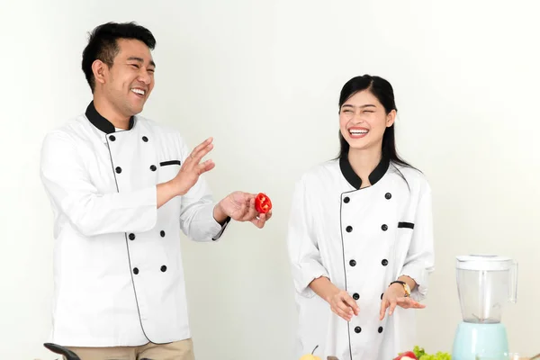 Asian chef man teaching his cook helper for slicing red chili pe