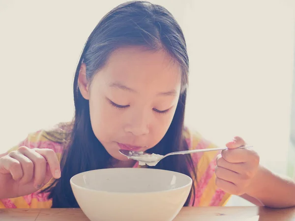 Carino ragazza asiatica mangia zuppa di riso per la colazione — Foto Stock