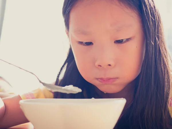 かわいいアジアの女の子は、朝食の米のスープを食べる — ストック写真