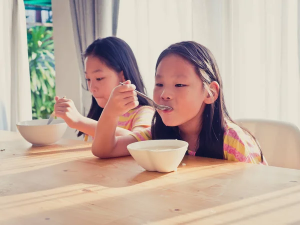 かわいいアジアの女の子は、朝食の米のスープを食べる — ストック写真