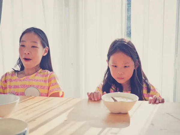 Cute Asian girl eats rice soup for breakfast