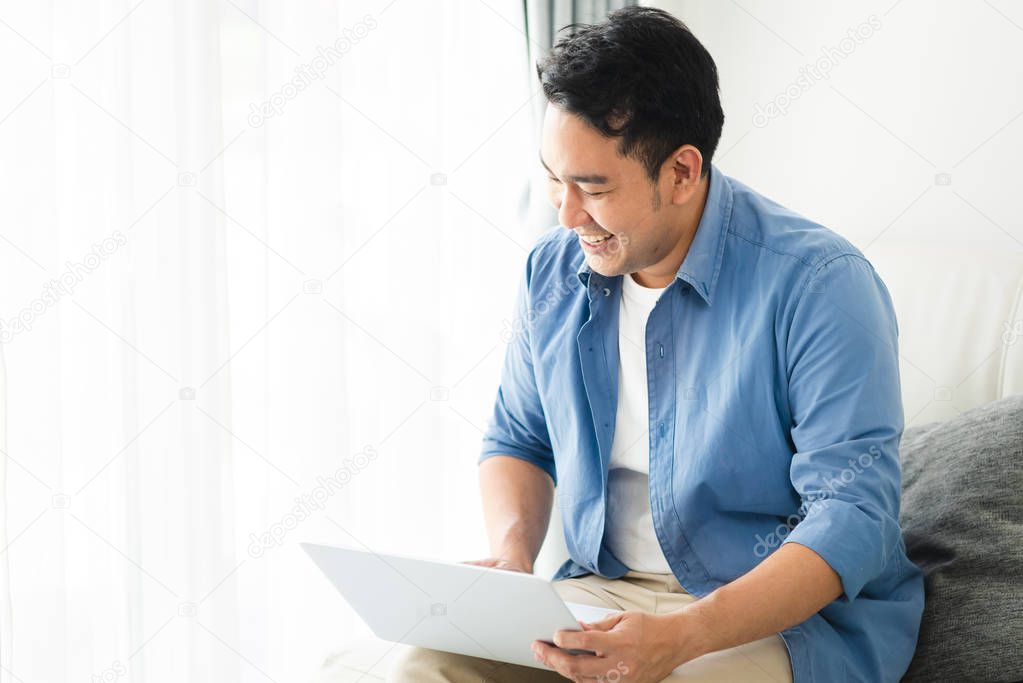 Asian man using laptop at home, lifestyle concept with copy spac