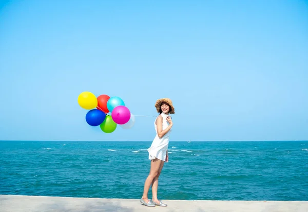 Šťastná Asijské žena v bílých šatech, držící barevné balónky na th — Stock fotografie