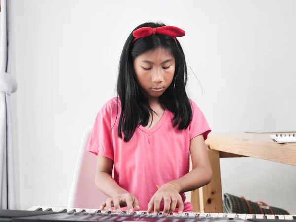 Menina asiática tocando piano teclado perto da janela em casa . — Fotografia de Stock