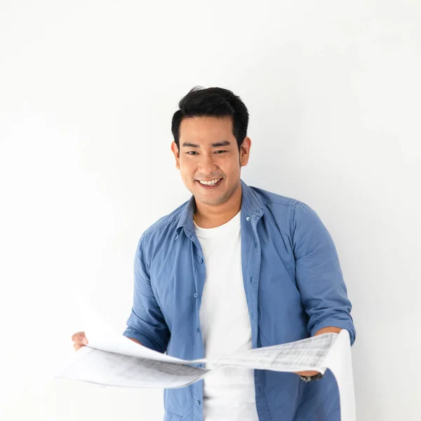 Šťastný asijský muž, který se dívá na plán v rukou proti bílým — Stock fotografie