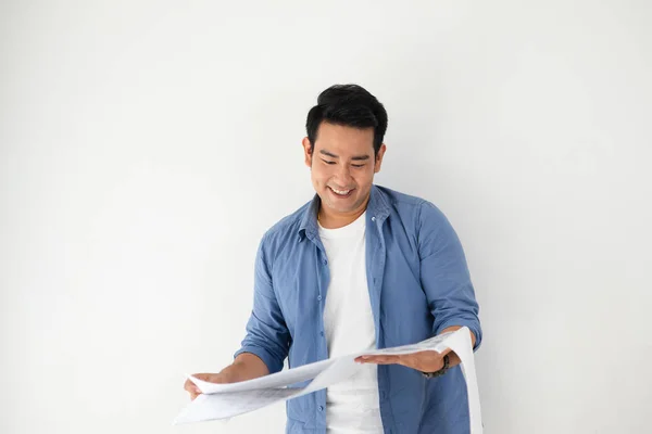 Feliz hombre Asian mirando el plano en sus manos contra el blanco —  Fotos de Stock