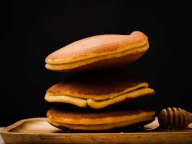 Bal şurubu ve siyah arka plan ile pancake.