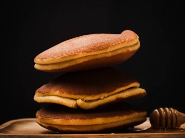 Bal şurubu ve siyah arka plan ile pancake.
