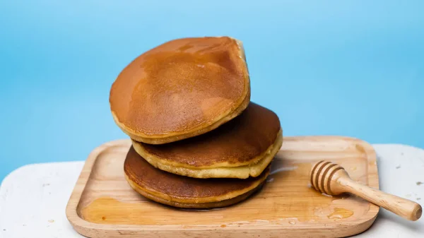 Pannenkoek met honing syrub en blauwe achtergrond. — Stockfoto