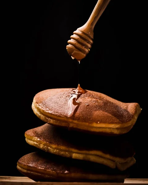 Pancake with honey syrup dipper and black background. — Stock Photo, Image