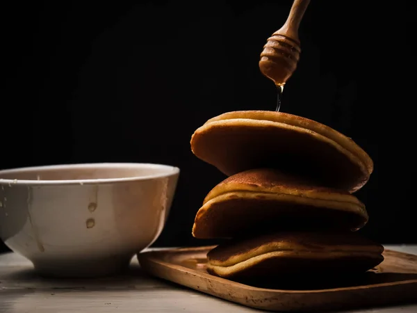 煎饼与蜂蜜糖浆浸渍和黑色背景. — 图库照片