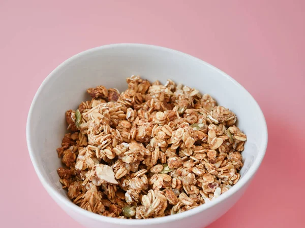 Cereal con escamas de granos enteros en tazón blanco sobre fondo rosa . — Foto de Stock